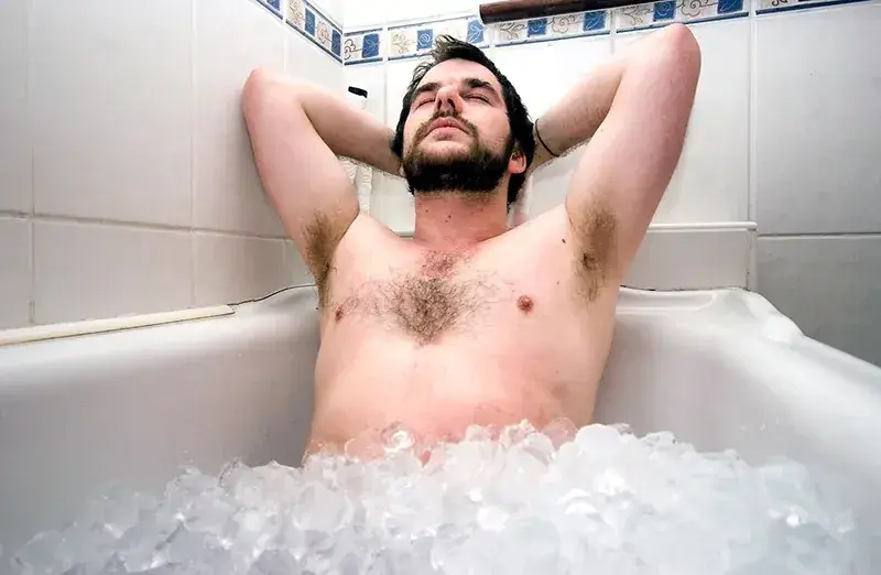 Athlete performing post-workout recovery routine with ice bath and hydration